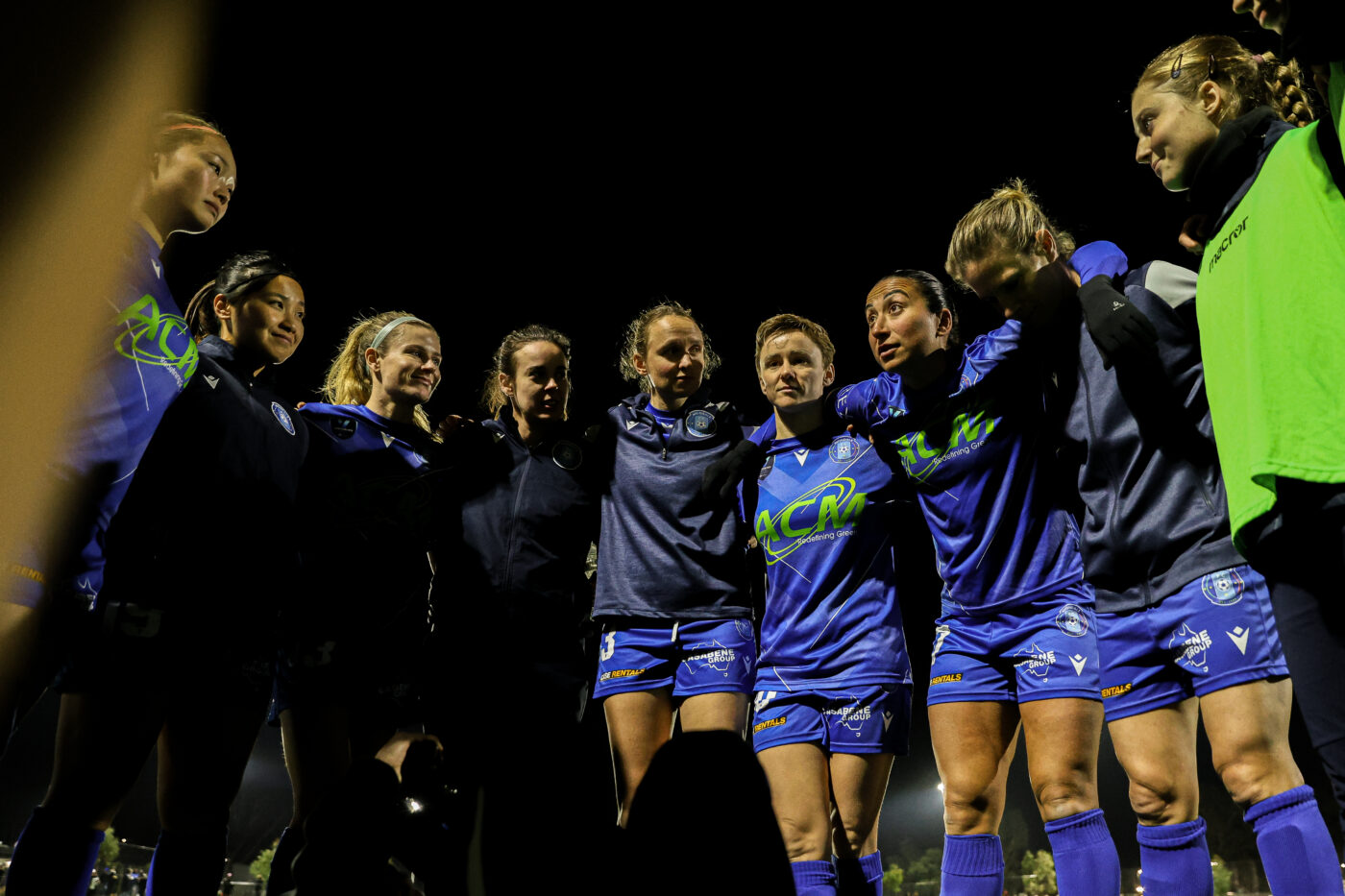 Players of Avondale FC women’s team embrace in a tight huddle, preparing with confidence.