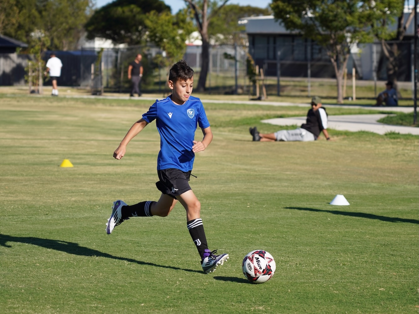 Junior Avondale FC footballer focused on ball control during outdoor practice in Melbourne.